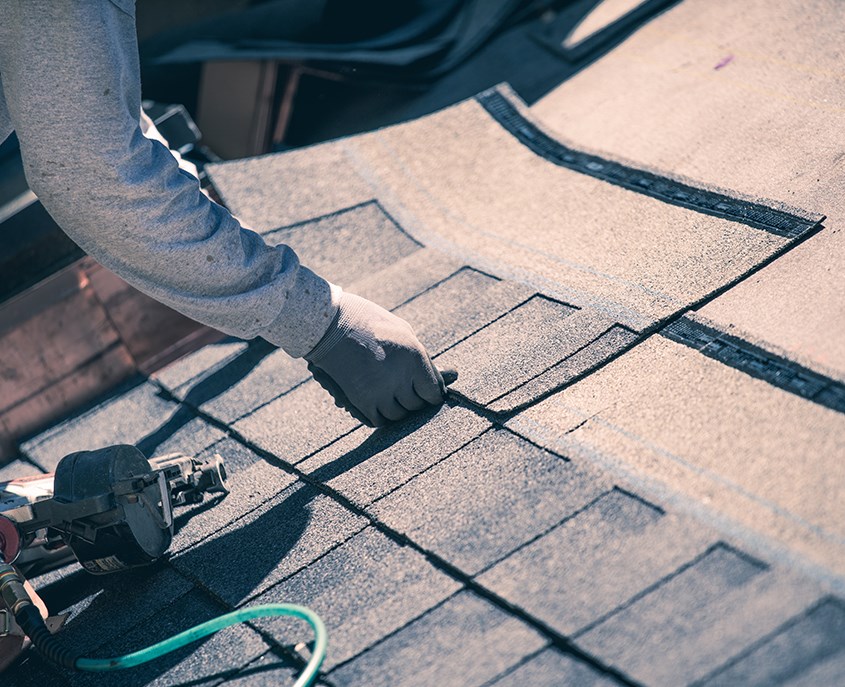 Roofer laying and installing shingles on residential roof in Gibbstown, NJ